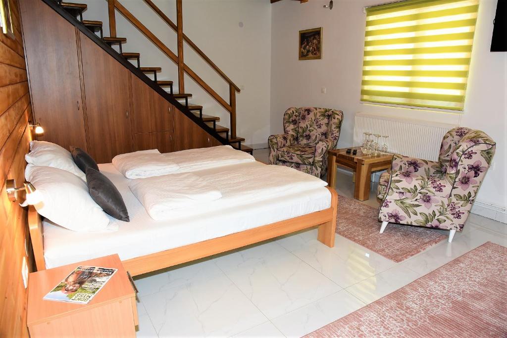 ein Schlafzimmer mit einem Bett, einer Treppe und 2 Stühlen in der Unterkunft Vila "Maglić" in Tjentište