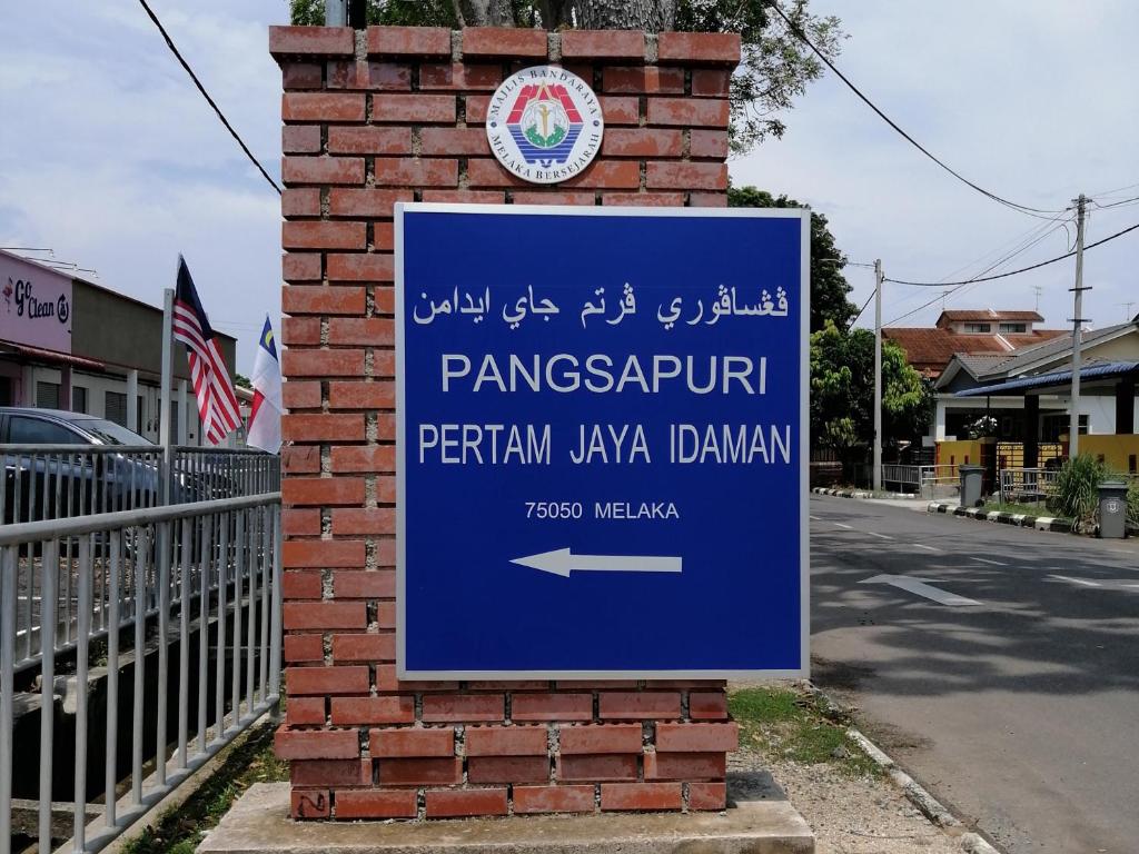 un signe bleu sur un mur de briques avec un signe pour une pharmacie dans l'établissement Amani Apartment Homestay, à Malacca