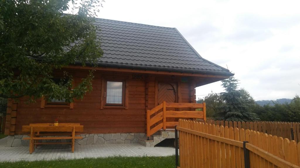 una cabaña de madera con una mesa delante en Domek Na kympkach en Istebna