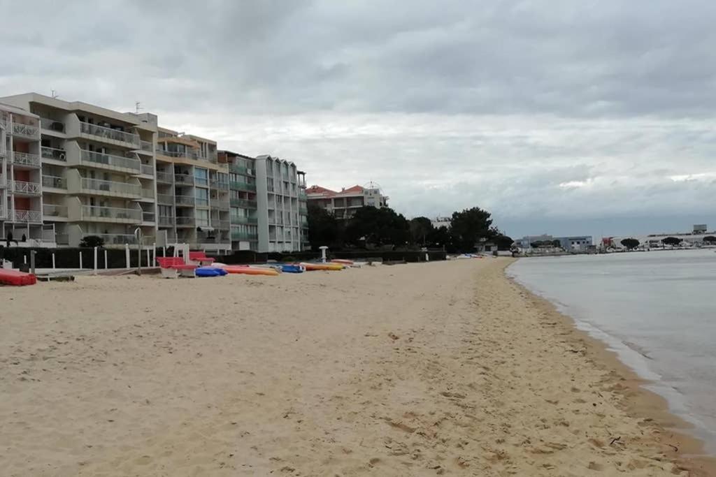 a sandy beach with some buildings and the water at T2 1ère ligne loggia vue mer 180 ° parking in Arcachon