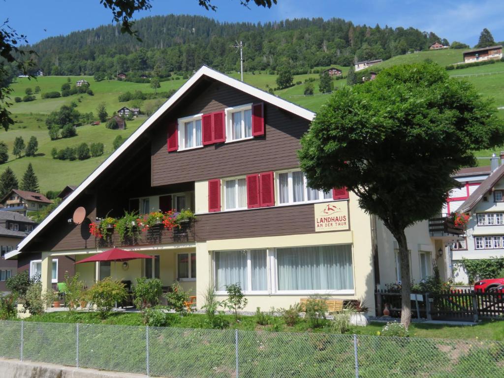 ein Haus mit roten Fensterläden und einem Baum in der Unterkunft Landhaus an der Thur in Alt Sankt Johann