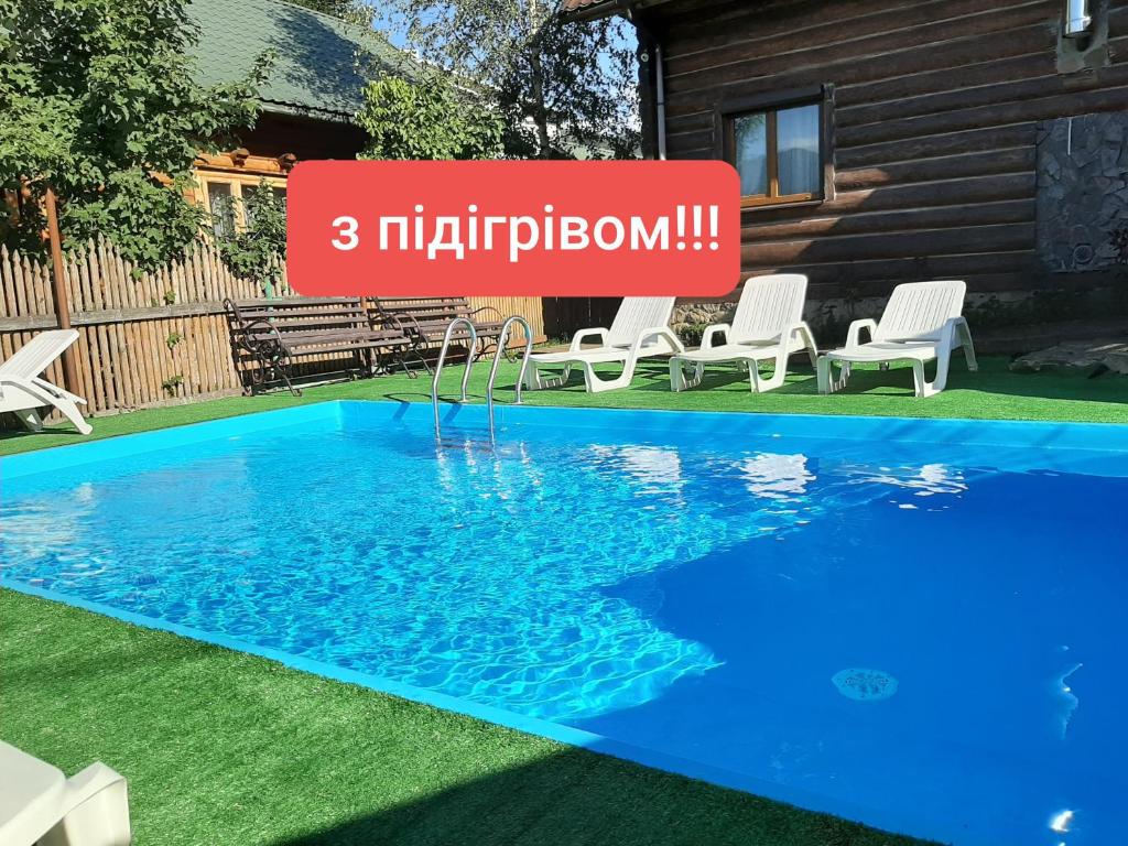 uma piscina com cadeiras e uma placa que lê multiplicação em Wood-House em Tatariv