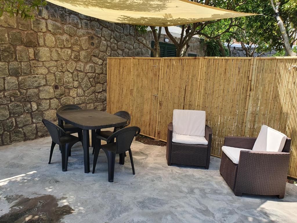 um pátio com uma mesa, cadeiras e um guarda-sol em Casa Mo Ma vacanze Ischia em Ischia