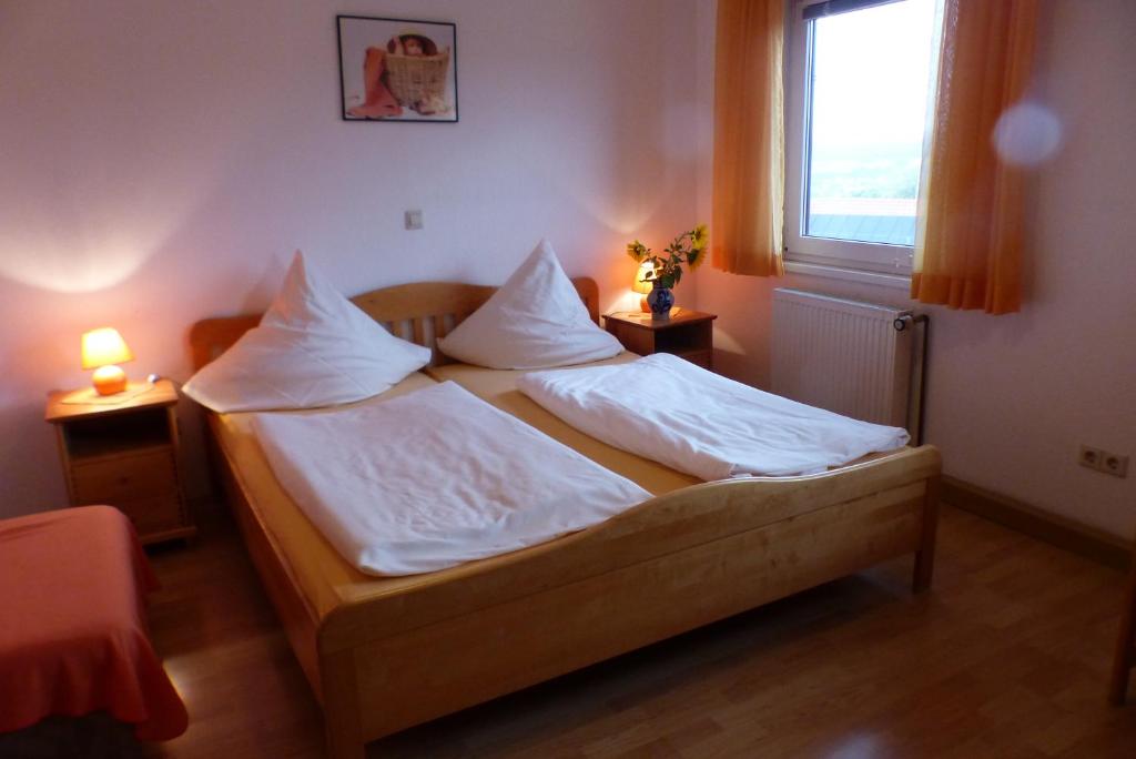 Schlafzimmer mit einem Bett mit weißer Bettwäsche und Kissen in der Unterkunft Pension Schreckhof in Mosbach