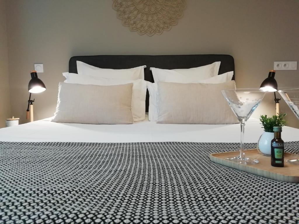 Bett mit weißen Kissen und einem Glas Wein in der Unterkunft Sweet Home studio Aix en Provence, terrasse, piscine, resto, in Aix-en-Provence