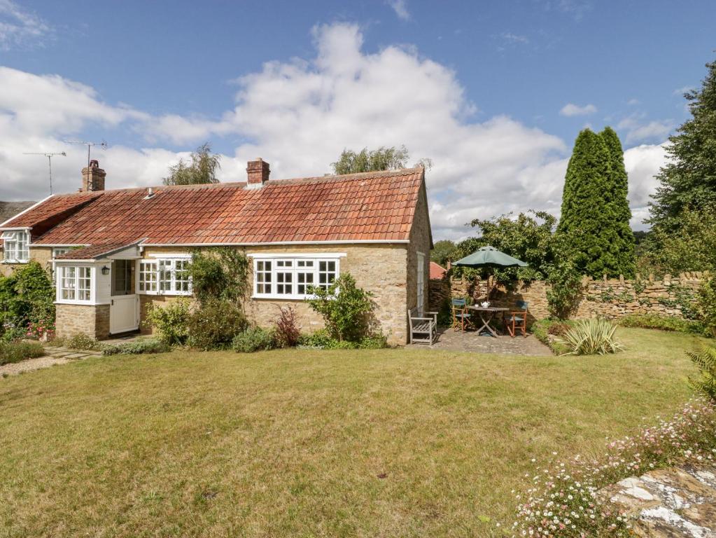 a brick house with a garden and a table at Yeoman Cottage in Crewkerne