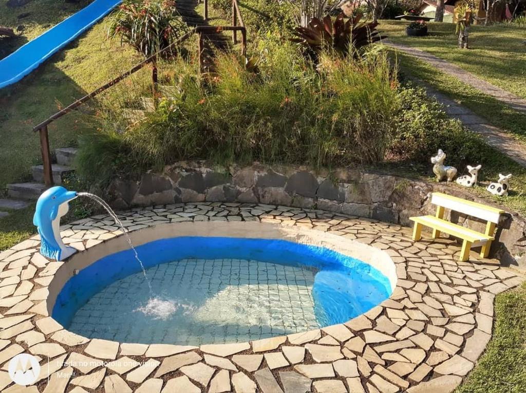 una pequeña piscina con una fuente de agua en un patio en Pousada Chácara do Rio, en Lumiar