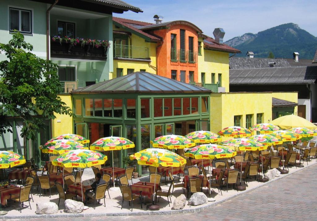 a group of tables and chairs with colorful umbrellas at Gasthof Zur Post in Bad Goisern