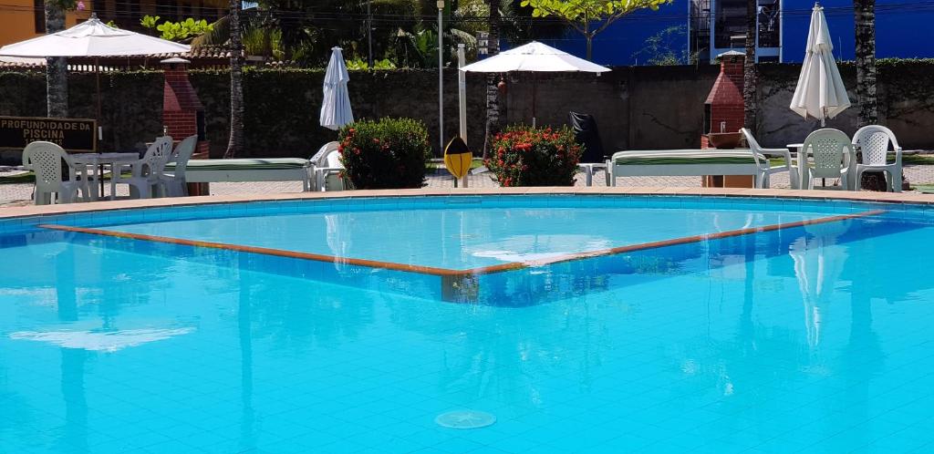 a large blue swimming pool with chairs and umbrellas at Apto 527 - Golden Village Taperapuã in Porto Seguro