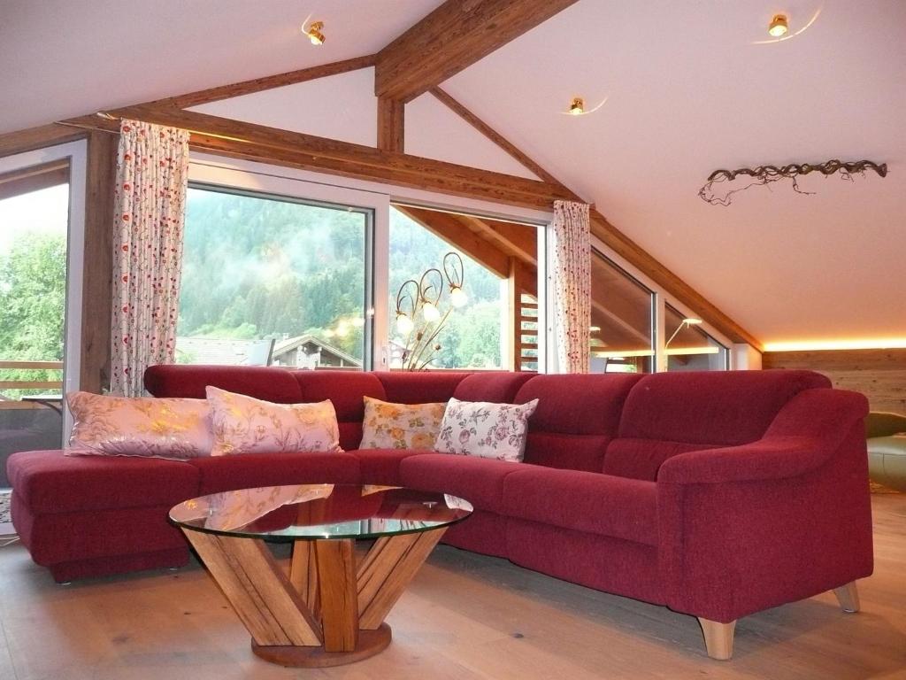 sala de estar con sofá rojo y mesa en Alpenstern Ferienwohnung en Pfronten