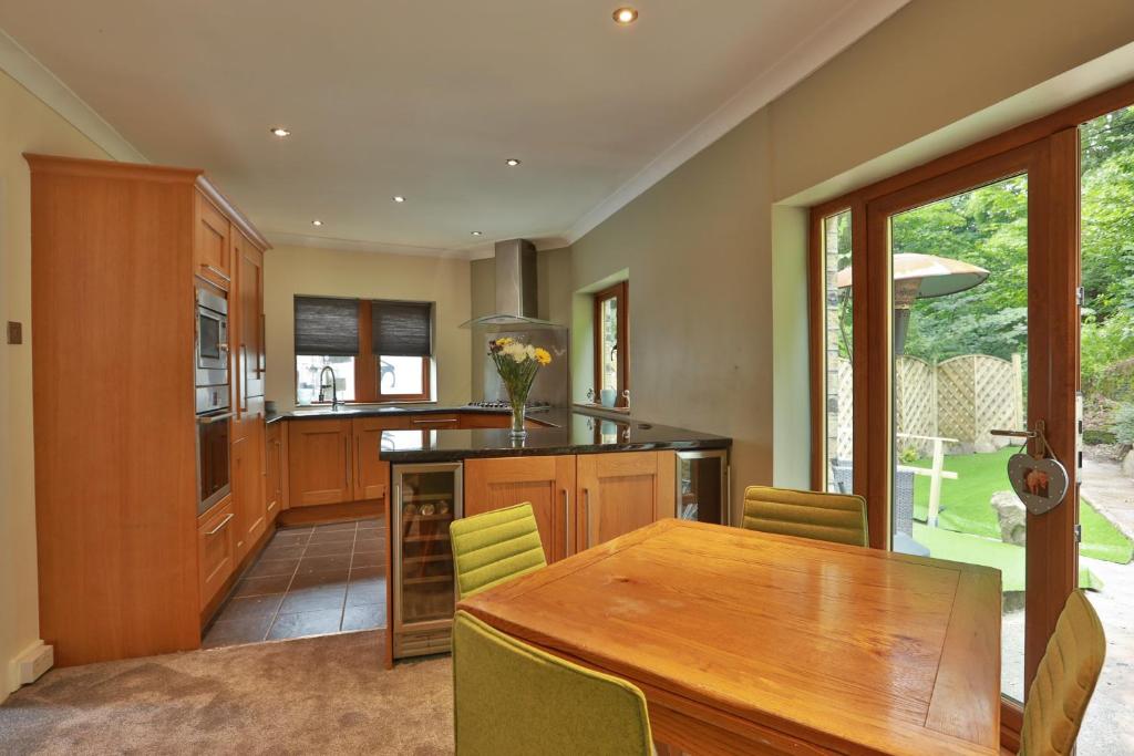 a kitchen with a wooden table and a dining room at Higgin Bridge House in Holmfirth
