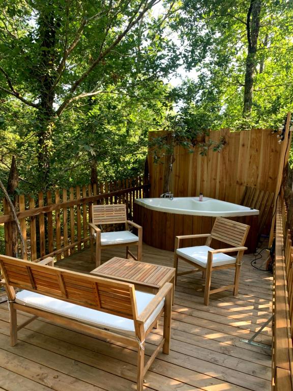 um deque de madeira com uma mesa, 2 cadeiras e uma banheira em Magic Roof Top Bus with big bath in the tree forest! em Mimizan