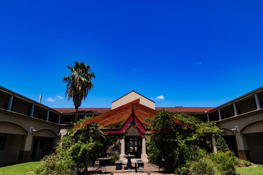 eine Außenansicht eines Gebäudes mit einer Palme in der Unterkunft Vineyard Court Designer Suites Hotel in College Station