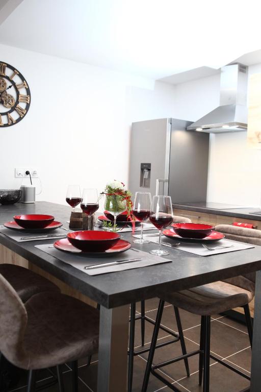 - une table avec des assiettes rouges et des verres à vin dans l'établissement Le Riesling Colmar centre Charmant appartement avec terrasse et parking gratuit, à Colmar