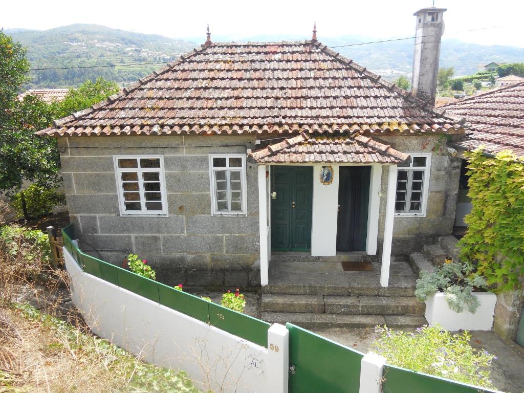 a small house with a white fence in front of it at Casa da D. Marquinhas in Santa Marinha do Zêzere