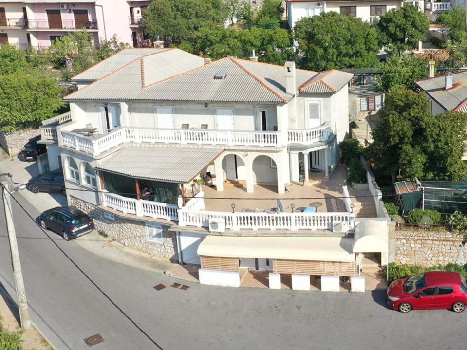 uma grande casa branca com um alpendre e um carro vermelho em Apartments and room Suza em Senj