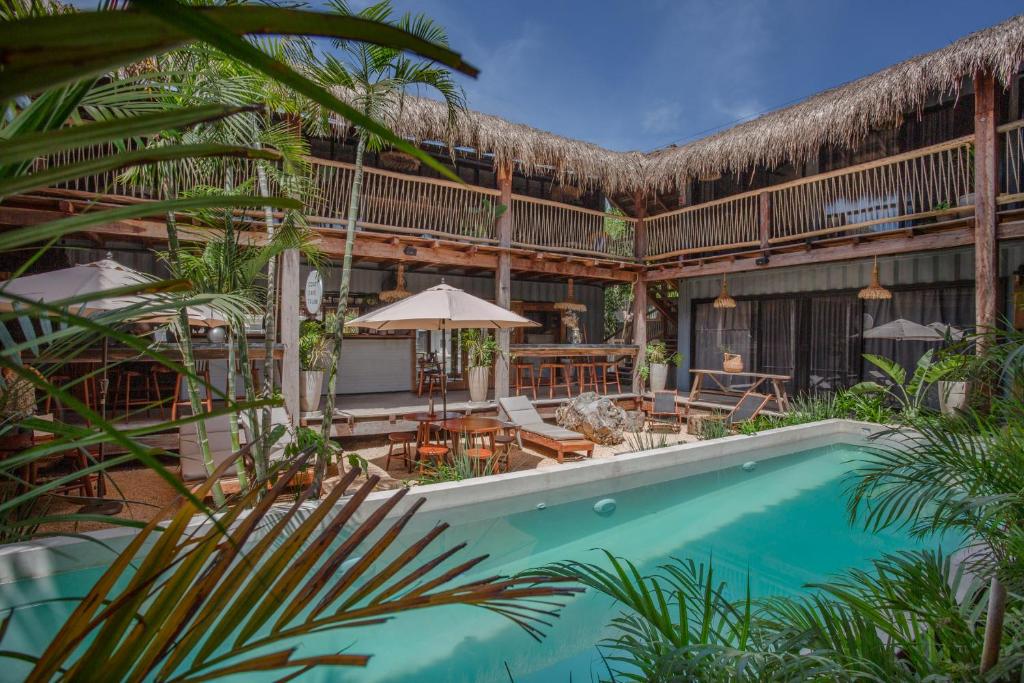 a resort with a swimming pool and a patio at Meteora Stay & Coffeehouse Tulum in Tulum