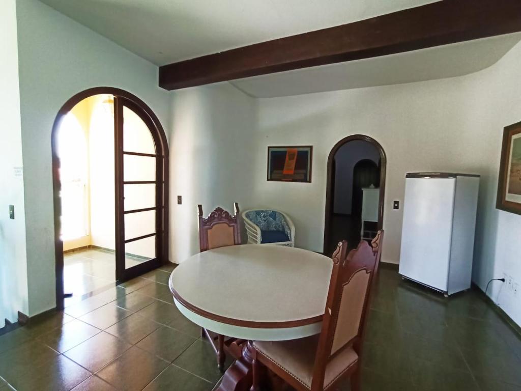 a dining room with a table and a refrigerator at Casa da Edna in Guarujá