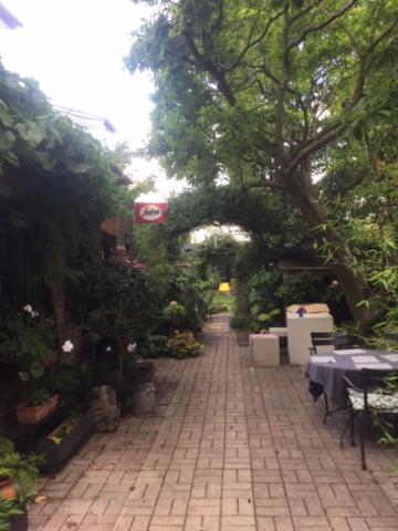 a brick walkway with tables and trees in a garden at The Coach House in Bickley