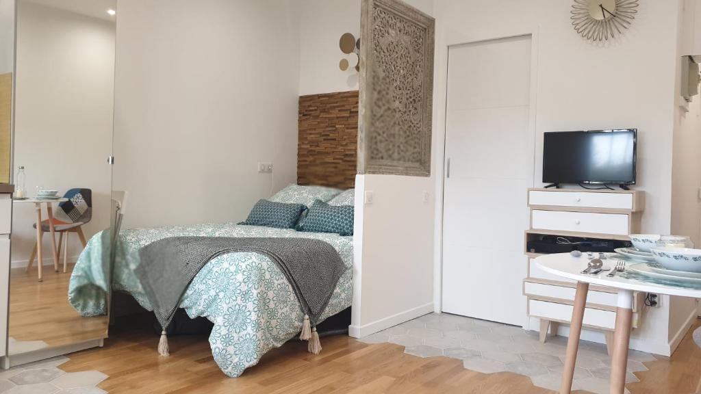 a bedroom with a bed and a tv and a table at Le Paon chaleureux et calme entre Paris et Disneyland in Ozoir-la-Ferrière