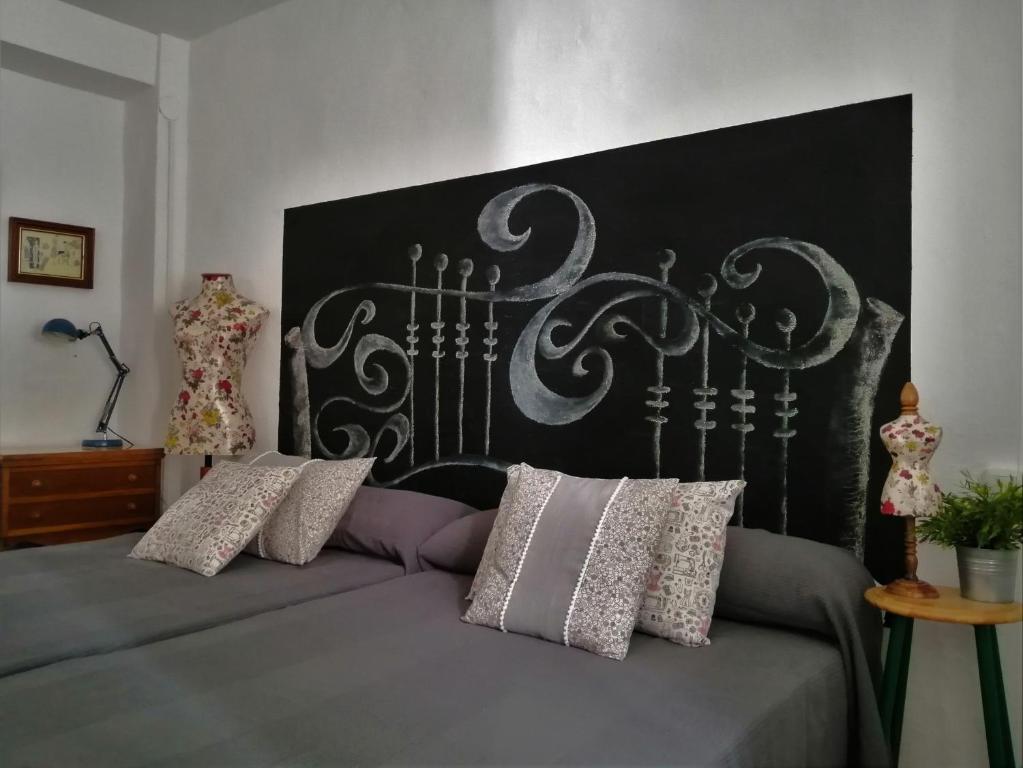 a bed with a black headboard and some pillows at Casa de La Costurera in Priego de Córdoba