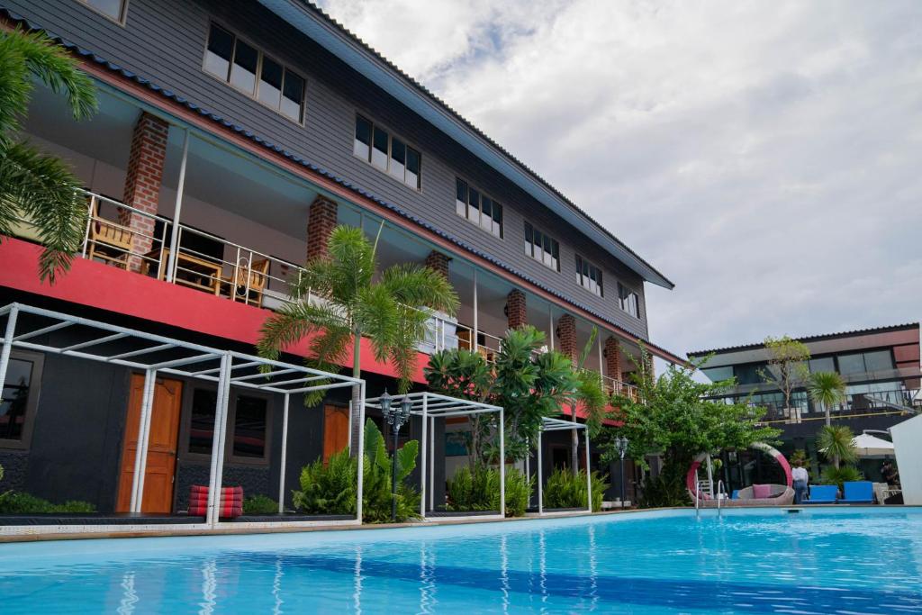 un hôtel avec une piscine en face d'un bâtiment dans l'établissement P.U. Inn Resort, à Phra Nakhon Si Ayutthaya