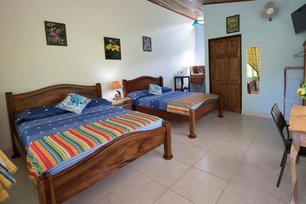 a bedroom with two beds and a desk at Hotel Sunshine Caribe in Puerto Viejo