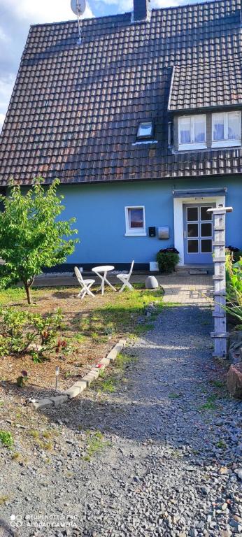 una casa azul con un banco delante en Kaya Ferienwohnungen, en Plettenberg