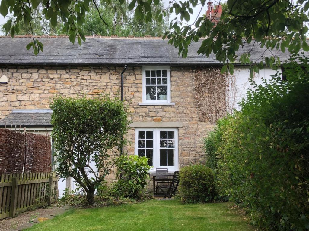 una casa de campo de piedra con un banco frente a ella en Mole Cottage, en Stocksfield