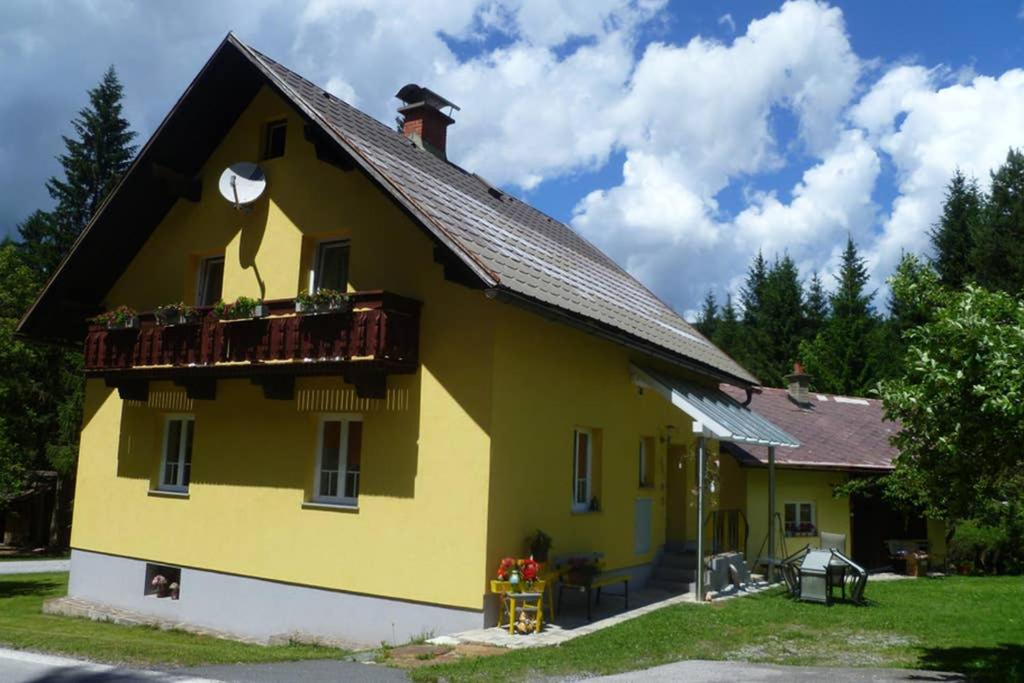 une maison jaune avec un balcon sur le côté dans l'établissement Gemütliches Ferienhaus am Waldrand, à Tröpolach