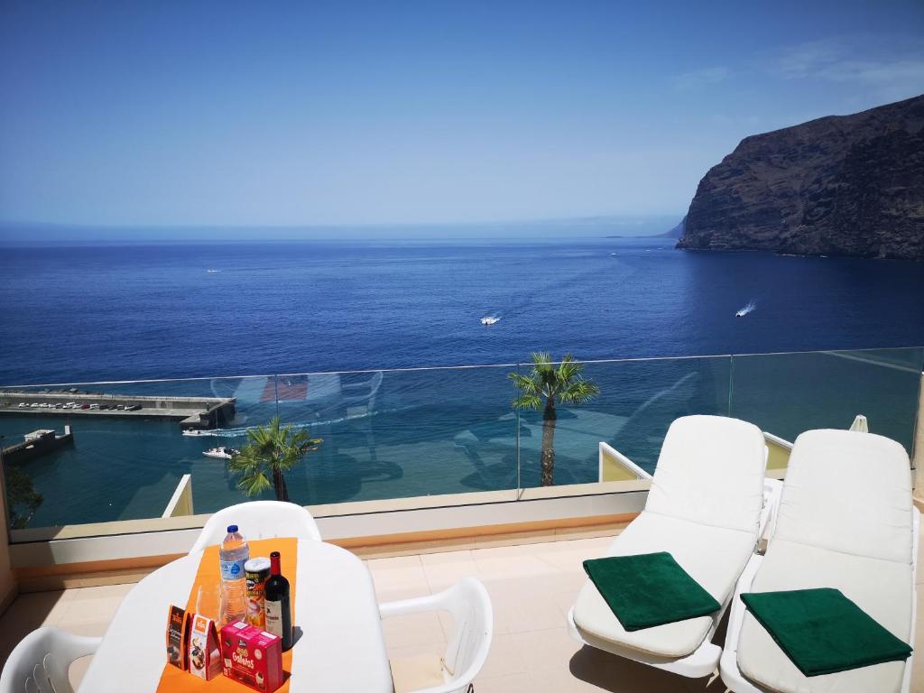 a balcony with white chairs and a view of the ocean at Magical Apt. with Sea View & Cliff in Acantilado de los Gigantes