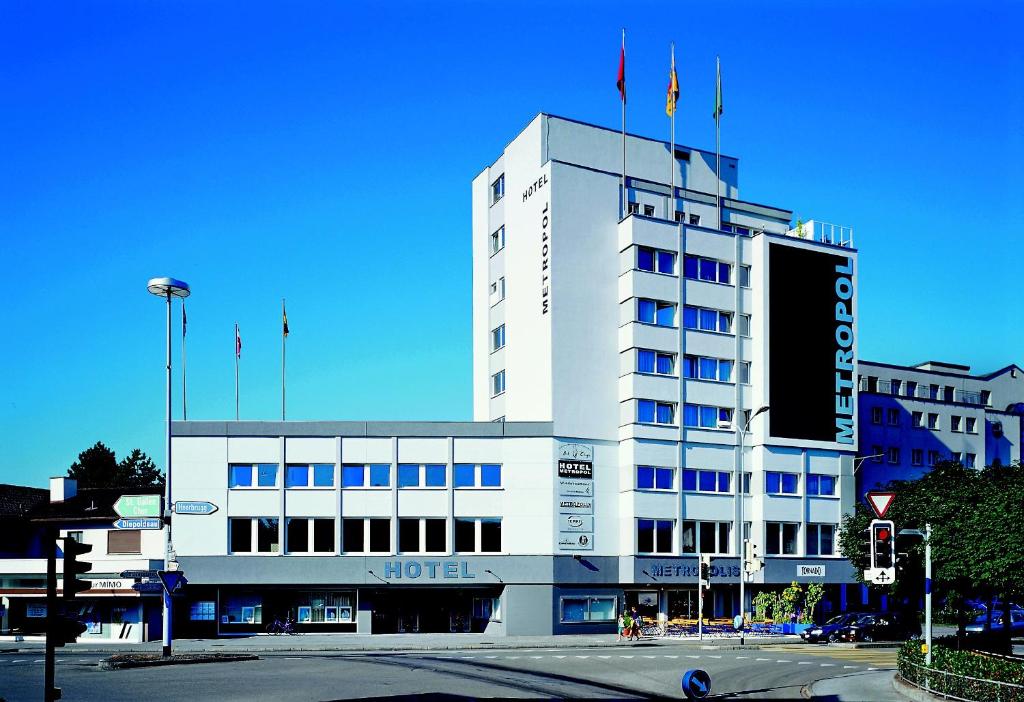 een wit gebouw met vlaggen erop bij Hotel Metropol in Widnau