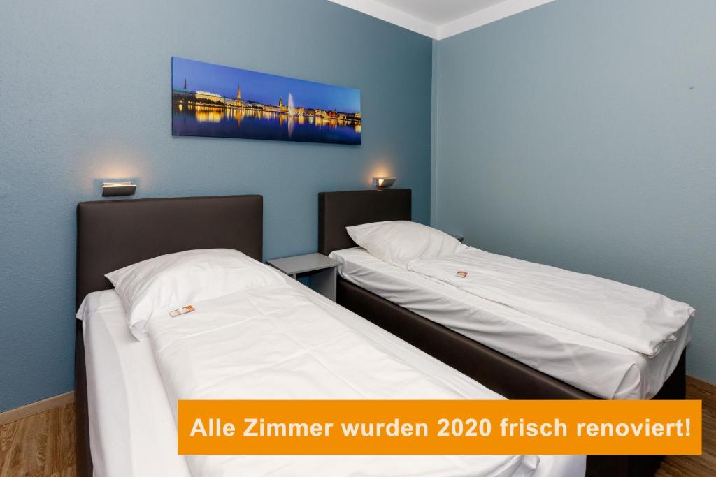 two beds in a room with a painting on the wall at Apart Hotel Sarstedter Hof in Sarstedt