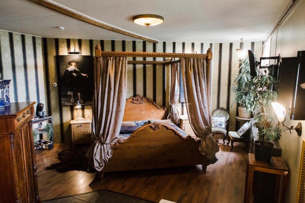 Logement Doosje في Warfstermolen: غرفة نوم مع سرير المظلة مع الستائر