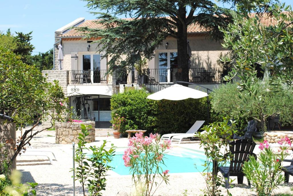 a house with a swimming pool and an umbrella at Terre de Bacchus in Vacqueyras