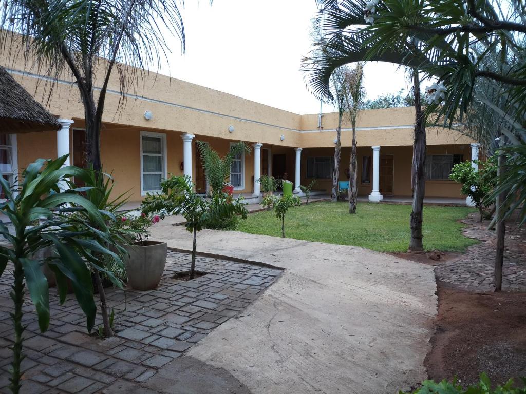 ein Haus mit Palmen davor in der Unterkunft Bonjour Inn Palapye in Palatswe