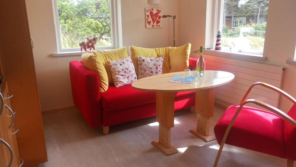 een woonkamer met een rode bank en een tafel bij Mini Beach House I Sylt/Rantum in Rantum