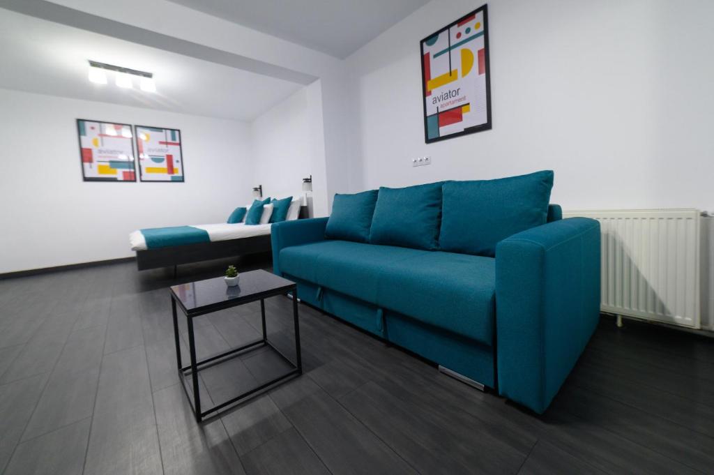 Una sala de estar con un sofá azul y una cama. en Aviator Apartament Alpha, en Deva