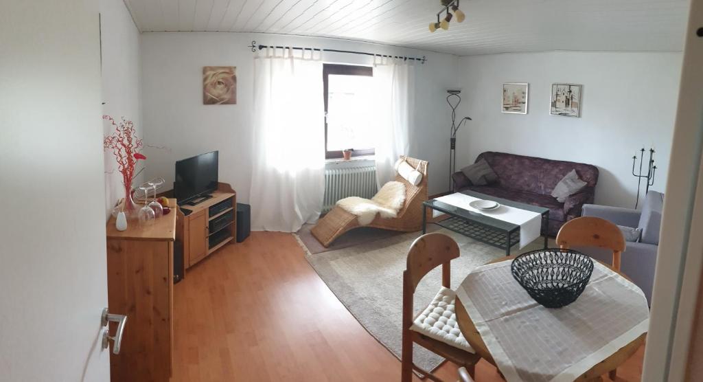 een woonkamer met een tafel en een bank bij Ferienwohnung -Zur Sonnenleite- in Dörfles