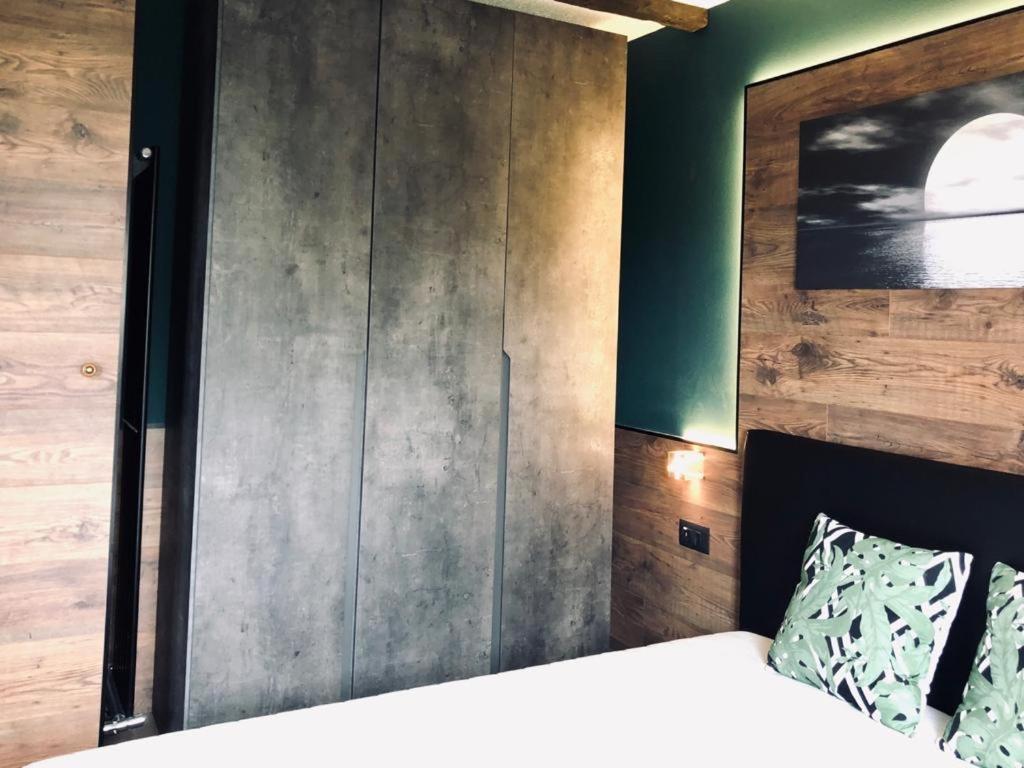 een slaapkamer met een bed en een houten muur bij Suite il sogno di Grebek in Passo del Tonale