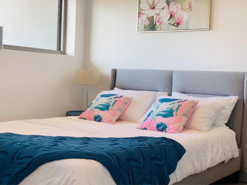 um quarto com uma cama com almofadas cor-de-rosa e azuis em Beautiful Home close to Shopping Mall and Train Hornsby em Hornsby