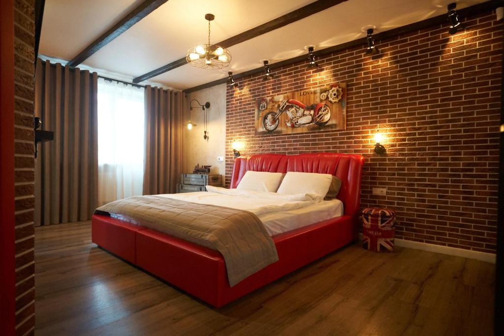 un letto rosso in una stanza con muro di mattoni di Garage a Kremenčuk