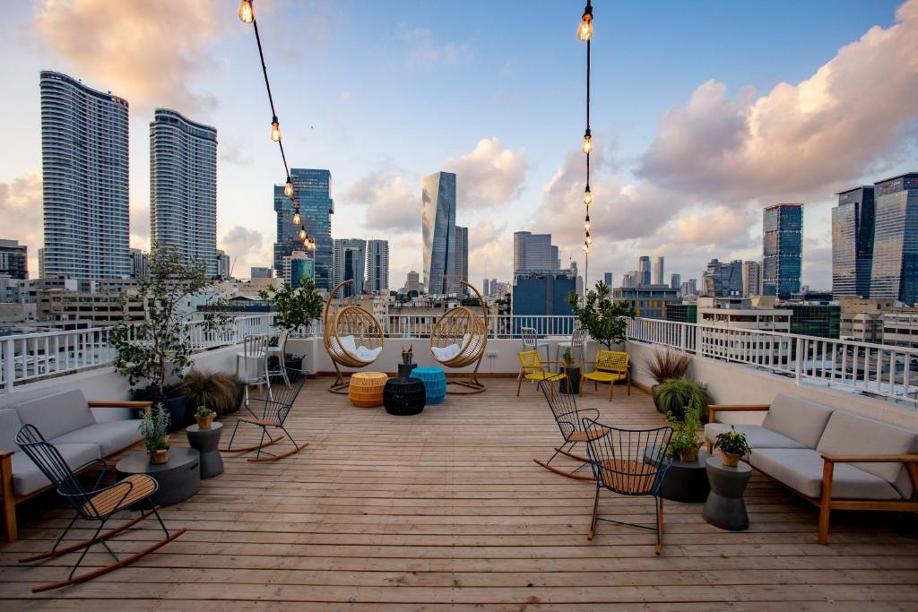 Una terraza en la azotea con sillas y sofás y un horizonte de la ciudad. en Domus Metro Hotel, en Tel Aviv