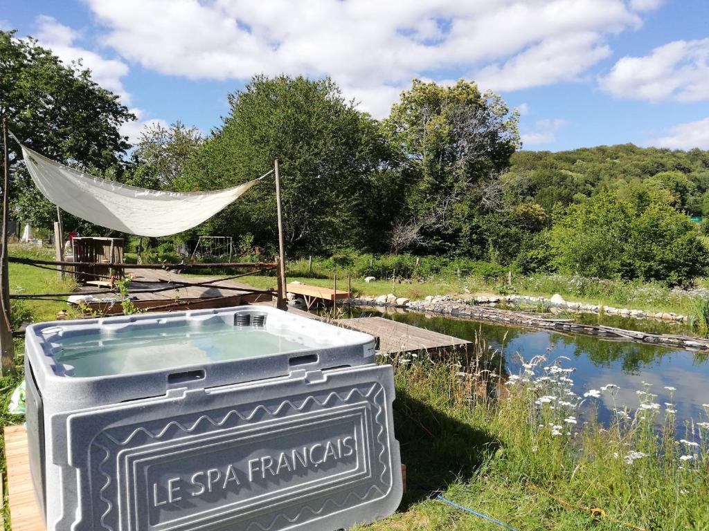 una bañera de hidromasaje en un jardín con un cartel junto a un estanque en La Maison Bleue23, en Sardent
