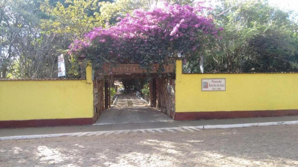 an archway with purple flowers on a yellow wall at Pousada Rancho do João in Pirenópolis