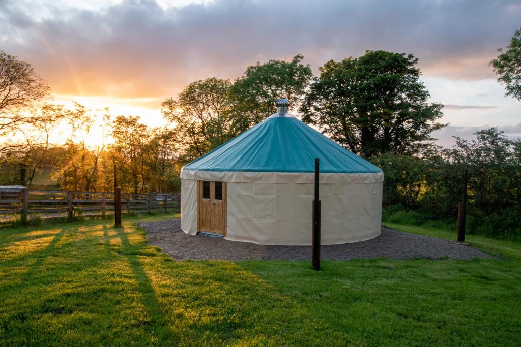 une tente dans un champ avec un coucher de soleil en arrière-plan dans l'établissement Loughcrew Glamping, à Oldcastle