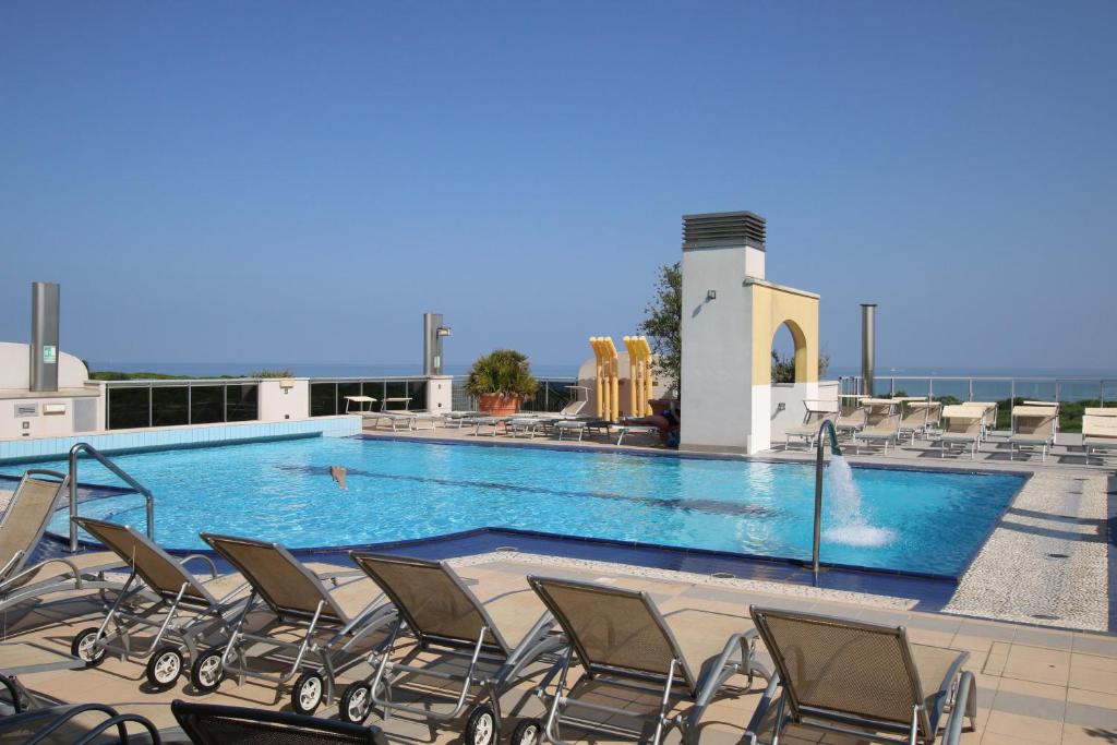 una piscina con sedie e scivolo d'acqua di Eraclea Palace Hotel 4 stelle S a Eraclea Mare