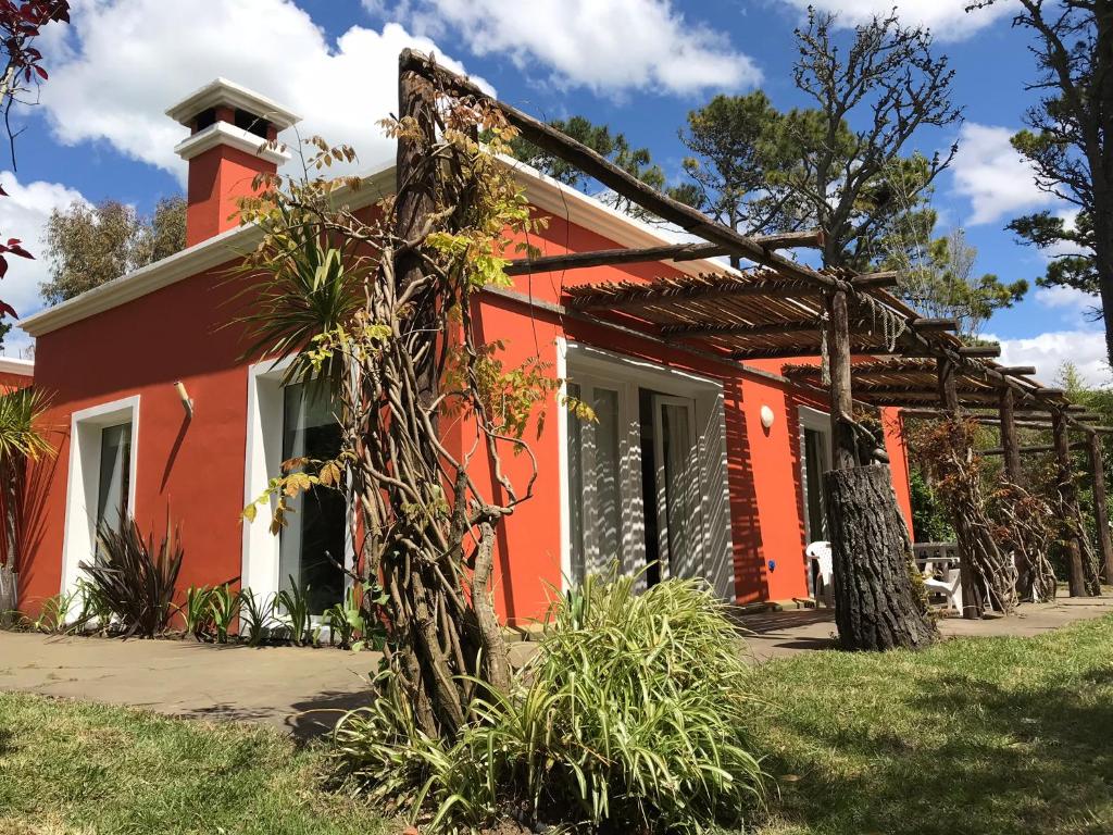 una casa roja con un árbol delante en Cul de Sac en Cariló