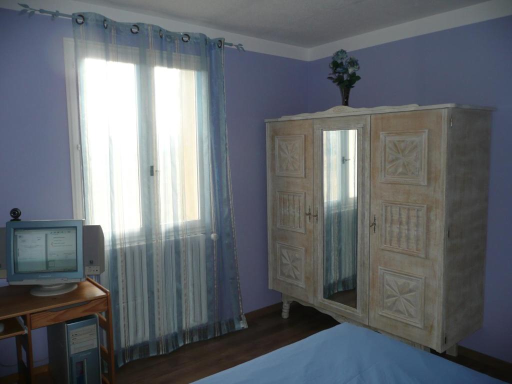 a bedroom with a television and a dresser and a window at CHAMBRES D&#39;HÔTES CLIMATISÉES avec CUISINE d&#39;ÉTÉ &quot;VILLA GOUR du PEYROL&quot; in Buisson
