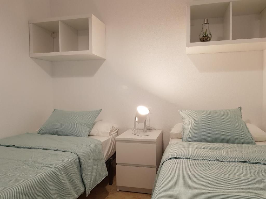 a bedroom with two beds and a lamp on a night stand at Appartement Torre La Mata in Torrevieja